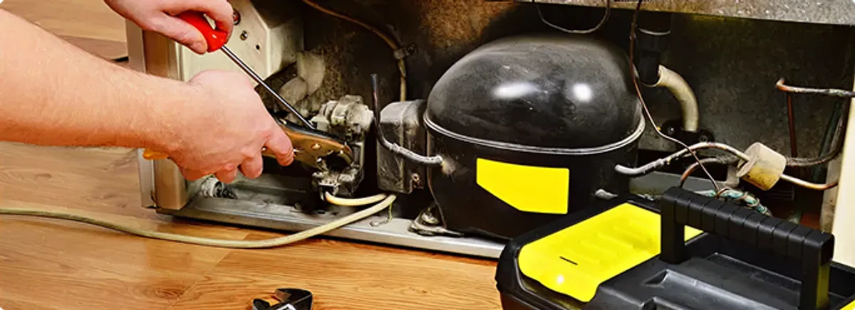 Refrigerator repair technician fixing the compressor and wiring in Emeryville, CA