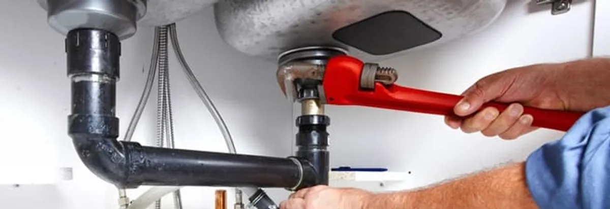 Garbage disposal repair technician tightening the sink drain and disposal connection in Oakland, CA