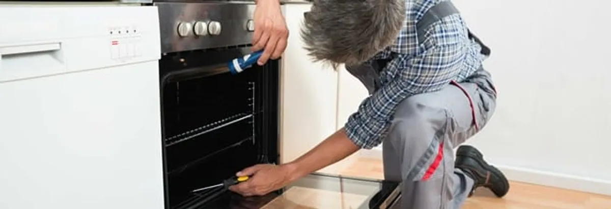 Oven repair technician inspecting and servicing an electric oven in Oakland, CA