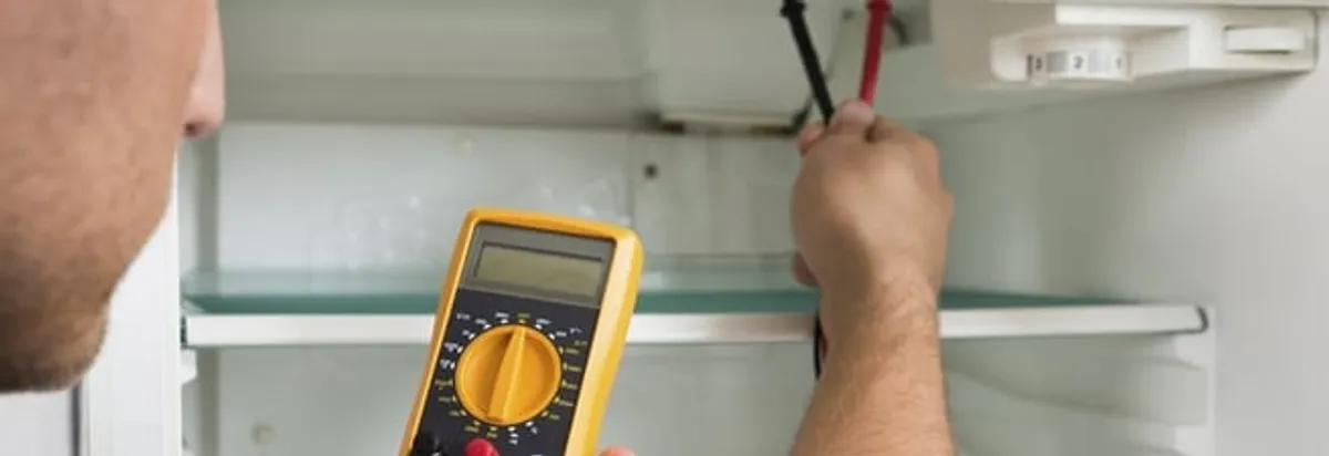 Refrigerator repair technician testing electrical components with a multimeter in Oakland, CA